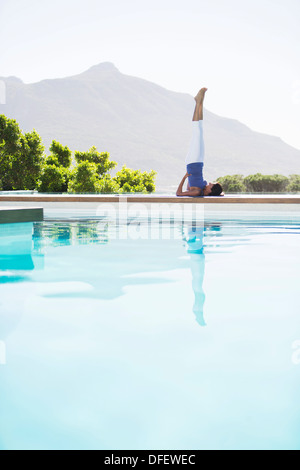 Woman practicing yoga at poolside Banque D'Images