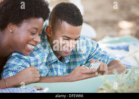 Couple using cell phone on blanket Banque D'Images