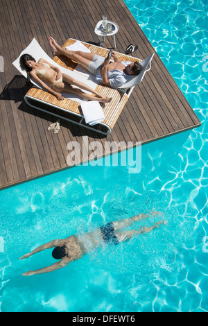 Couple de détente sur les chaises longues au bord de la piscine Banque D'Images