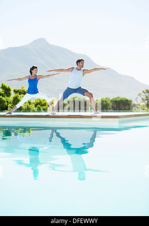 Couple practicing yoga at poolside Banque D'Images