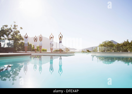 Les personnes pratiquant le yoga at poolside Banque D'Images