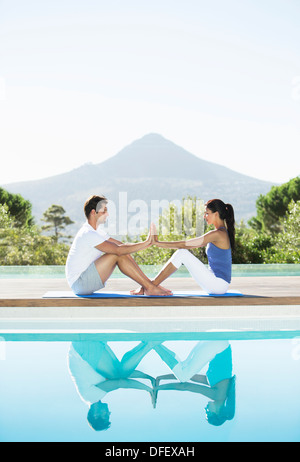 Couple practicing yoga poolside Banque D'Images