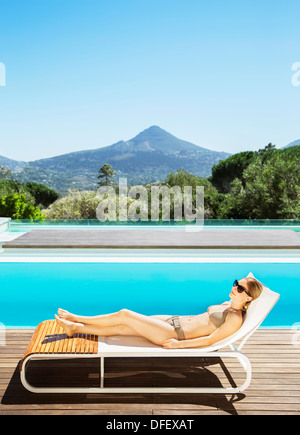 Woman relaxing on lounge chair at poolside