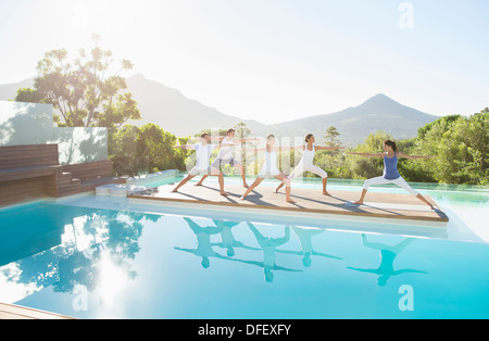 Les personnes pratiquant le yoga at poolside Banque D'Images