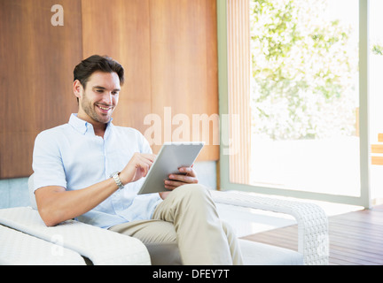 Man using digital tablet in armchair Banque D'Images