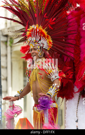 Carnaval d'hommes portant une coiffe élaborée interprète de plumes rouges sur un flotteur dans la procession, le carnaval de Notting Hill, Londres, Angleterre Banque D'Images