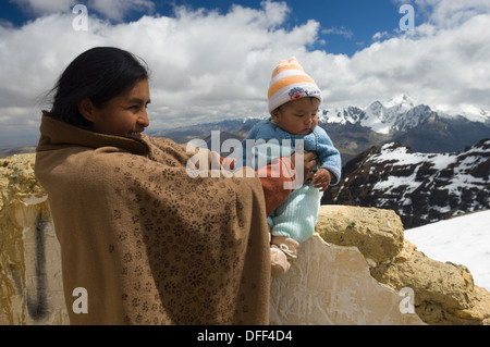 Mère bolivienne tenant son enfant nouveau-né au 5421 mètres (17 785 pieds) Sommet du Chacaltaya, comme une tradition locale, près de La Paz, Bolivie Banque D'Images