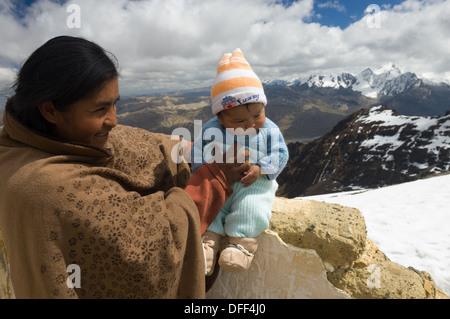 Mère bolivienne tenant son enfant nouveau-né au 5421 mètres (17 785 pieds) Sommet du Chacaltaya, comme une tradition locale, près de La Paz, Bolivie Banque D'Images