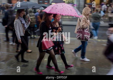 Les Londoniens promenade le long du centre de Londres, Oxford Street au cours de la pluie d'automne. Banque D'Images