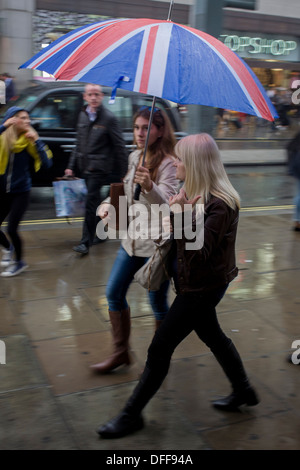 Les Londoniens promenade le long du centre de Londres, Oxford Street au cours de la pluie d'automne. Banque D'Images