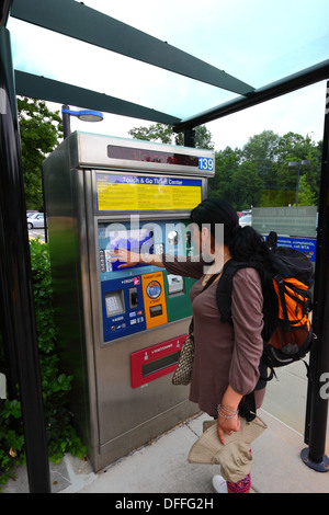 Fille hispanique achetant un billet en utilisant un distributeur automatique de billets avec écran tactile, Falls Road Light Rail Stop, Baltimore County, Maryland, États-Unis Banque D'Images