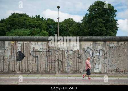 Un homme qui marche en avant du mur de Berlin à la Bernauer Strasse, Berlin, Allemagne. Banque D'Images