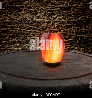 Sel de l'himalaya comme une lampe sur une vieille table en bois en face d'un mur de pierre Banque D'Images