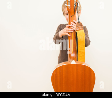 Jeune fille, 4 ans, joue avec une guitare acoustique. Banque D'Images