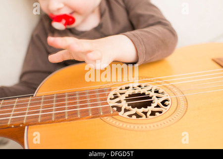 Jeune fille, 4 ans, joue avec une guitare acoustique. Banque D'Images