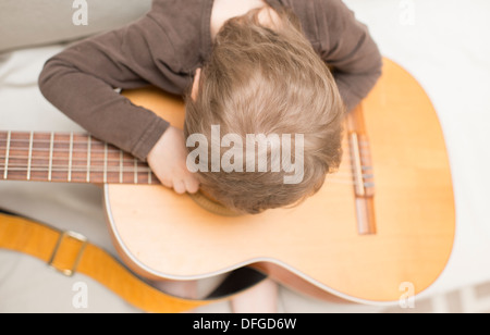 Jeune fille, 4 ans, joue avec une guitare acoustique. Banque D'Images