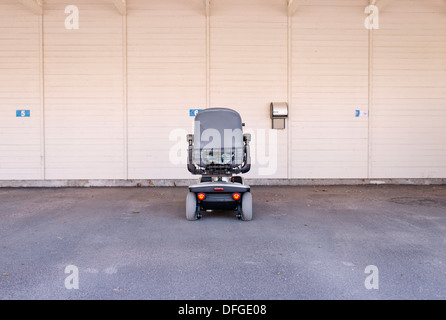 Un fauteuil roulant électrique seul dans un garage. Image conceptuelle de vieux, mobilité et solitaire Banque D'Images