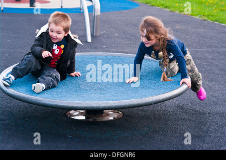 Frère et Sœur tourner en rond sur un rond-point de Jeux Banque D'Images