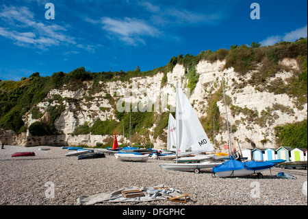 Bateaux à voile sur la plage de galets sous les falaises blanches de la bière à Devon, Angleterre Royaume-uni Banque D'Images