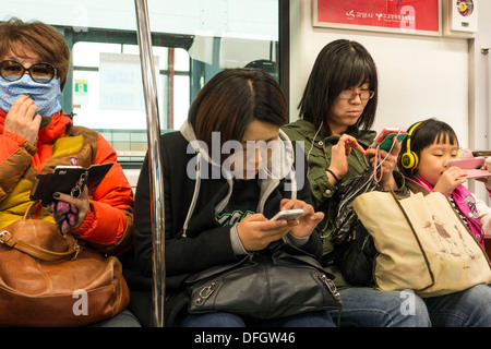 Les passagers utilisant des téléphones mobiles on Subway train, Séoul, Corée Banque D'Images