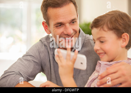 Père et fils using cell phone Banque D'Images