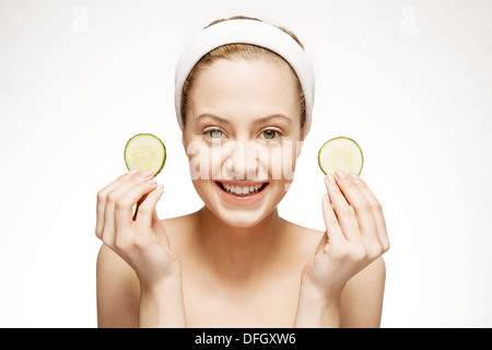 Smiling woman holding tranches de concombre Banque D'Images