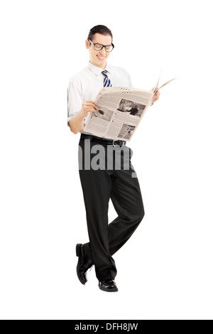 Portrait of a smiling woman leaning against wall et lire un journal Banque D'Images