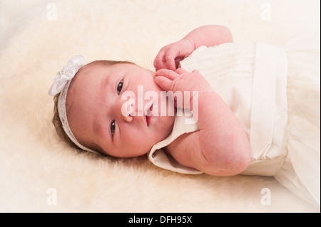 Bébé nouveau-né fille aux cheveux blancs dans la bande robe de couleur crème Banque D'Images