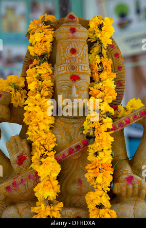 Déesse hindoue en pierre statue de Saraswati et de fleurs. L'Andhra Pradesh, Inde Banque D'Images