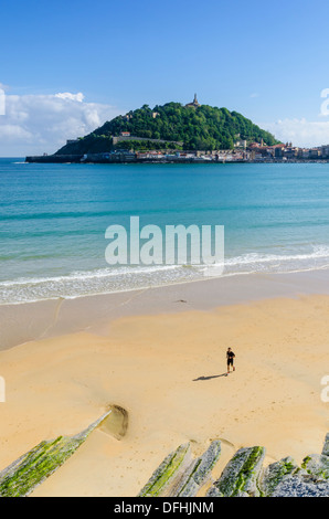 Homme qui court sur la plage Playa de la Concha avec vues vers le Monte Urgull, San Sebastian, Espagne Banque D'Images