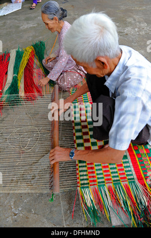 Personnes âgées faisant main vietnamiens reed colorés de tapis. Banque D'Images