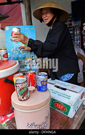 Vietnamese woman selling beer en conserve et les boissons portant un chapeau conique traditionnel. Banque D'Images