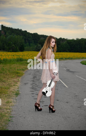 Jeune femme seule est au violon par country road Banque D'Images