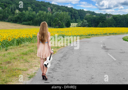 Jeune femme seule avec violon par country road Banque D'Images