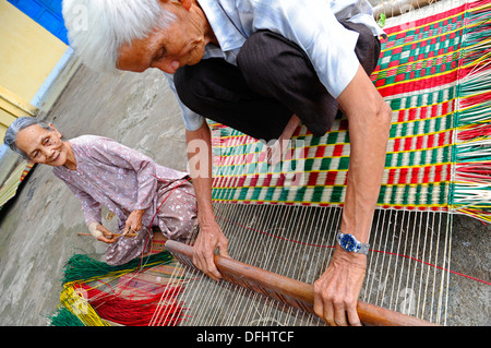 Personnes âgées faisant main vietnamiens reed colorés de tapis. Banque D'Images