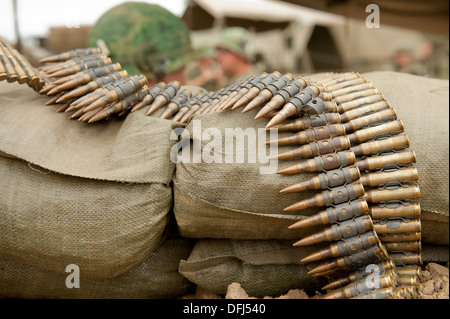 Pièces de munitions sur un clip ceinture de sécurité reposant sur le sable d'un dug-out. Banque D'Images