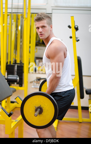 Beau jeune homme de l'exercice, l'exercice de biceps avec barbell at gym Banque D'Images