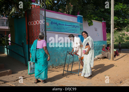 L'homme Indien et les femmes marcher vers le Sri Sathya Sai Baba l'hôpital d'approche mobile à une école de village. L'Andhra Pradesh, Inde Banque D'Images