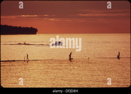 Au coucher du soleil sur le lac Érié, on voit des citoyens faire de la navigation de plaisance et pêcher malgré les eaux polluées, illustrant à la fois la beauté et les défis environnementaux auxquels le lac est confronté. Banque D'Images