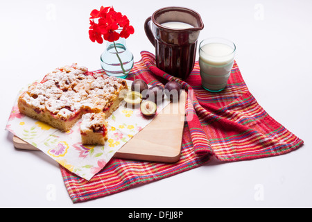 Gâteau aux prunes et tasse de lait sur fond blanc. Banque D'Images