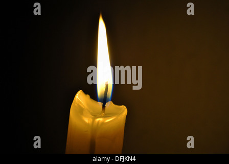 La seule bougie allumée dans l'obscurité, brûle avec une flamme lumineuse Banque D'Images
