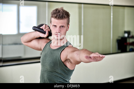 Jeune homme attrayant l'entraînement avec kettlebell, working out in gym Banque D'Images