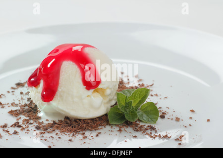 Crème glacée à la vanille avec une tige de menthe et de sirop de groseilles rouges Banque D'Images