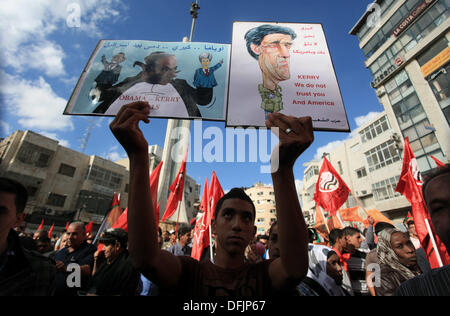 Ramallah, Cisjordanie, territoire palestinien. 6Th Oct 2013. Un palestinien est titulaire d'une caricature de la secrétaire d'Etat John Kerry et une affiche avec l'image du Premier ministre israélien Benjamin Netanyahu holding up deux marionnettes à main, le président américain Barack Obama (G) et le secrétaire d'Etat américain John Kerry (R) au cours d'une manifestation par des centaines de Palestiniens dans la ville de Ramallah, en Cisjordanie, le 6 octobre 2013, demandant au président palestinien Mahmoud Abbas à se retirer des négociations avec Israël. Intervenant devant l'Assemblée générale des Nations unies la semaine dernière, Abbas a mis en garde l'Organisation des Nations Unies que de paix négocié nous Banque D'Images