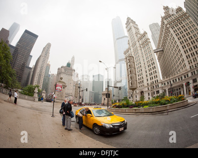 Une vue de trois personnes fisheye attraper un taxi sur North Michigan Avenue à Chicago, Illinois sur un jour nuageux, ciel couvert. Banque D'Images