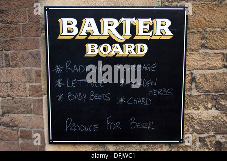 Un conseil de troc proposant une bière pour les produits frais à l'extérieur d'un pub de village dans le Derbyshire, Angleterre, Royaume-Uni Banque D'Images