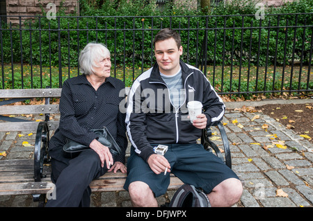 Un jeune homme et sa grand-mère parler et fumer des cigarettes sur un banc dans la ville de New York Banque D'Images