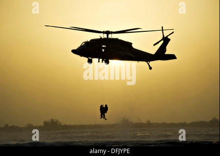 L'Armée américaine UN UH-60 Black Hawk hisse des bérets verts à partir du 7ème groupe des forces spéciales silhouetté contre le soleil du 25 juillet 2013 au large de la côte de Roatan, Honduras. Banque D'Images