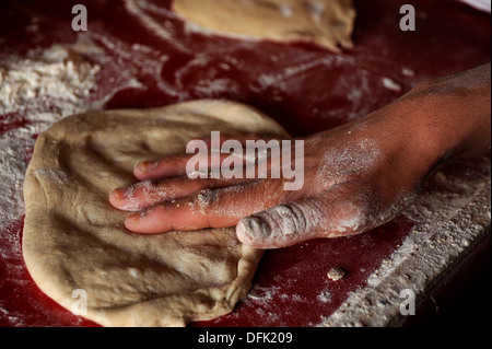 Un Afghan baker aplatit la pâte utilisée pour faire du pain naan traditionnel afghan à son blocage des routes le 7 juin 2010 dans un petit village près de Kandahar, en Afghanistan. Banque D'Images