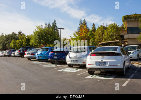 Plug-in voitures électriques stationnés dans les places de stationnement réservées aux voitures EV à un terrain de stationnement de l'entreprise Banque D'Images